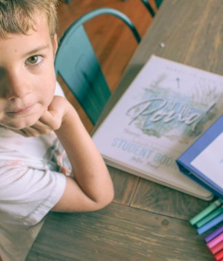 kindergartener at table with homeschool curriculum and markers