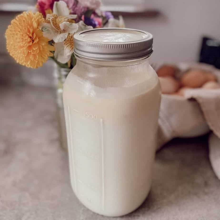 raw milk in half gallon mason jar with flowers and eggs behind