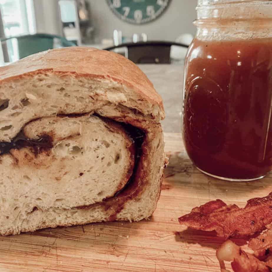 sourdough cinnamon swirl bread next to canned apple butter and cooked bacon