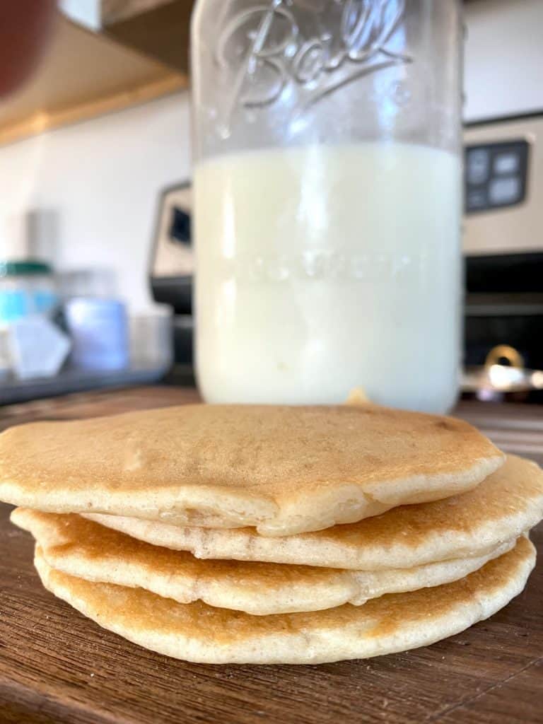 sourdough pancakes stacked in front of raw milk