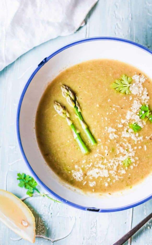 creamy asparagus soup topped with parmesan cheese and asparagus spears