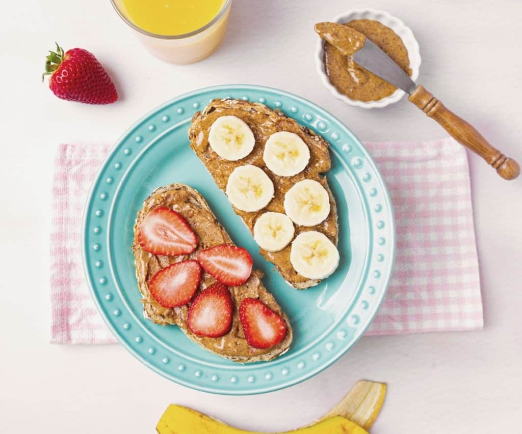 sourdough toast topped with almond butter and bananas and strawberries