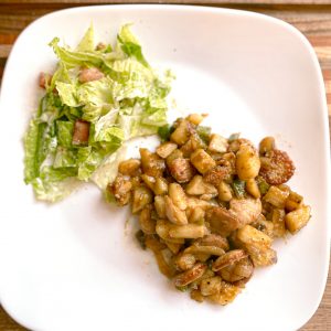 smothered potatoes and sausage with side salad on white plate