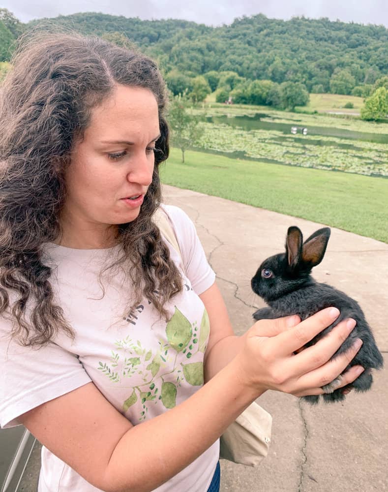 woman holding black rabbit outside