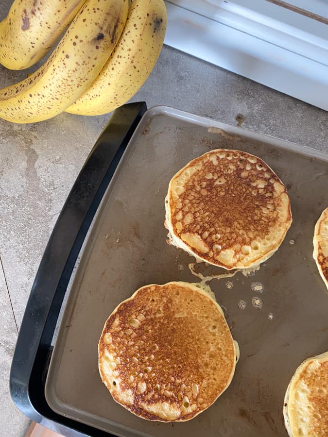 sourdough banana pancakes cooking on griddle