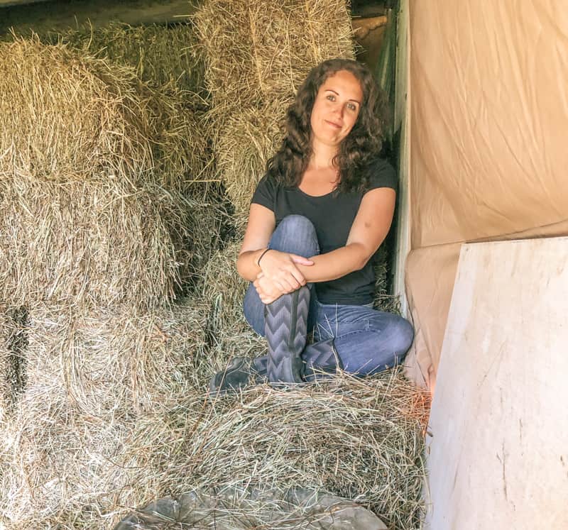 woman sitting on pile of square hay bales