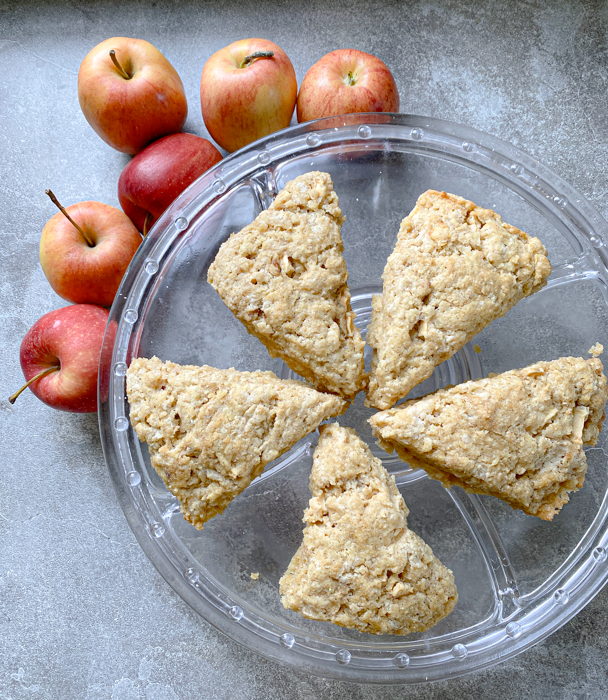 5 sourdough einkorn scones on a glass dish. The dish is surrounded by whole red apples.