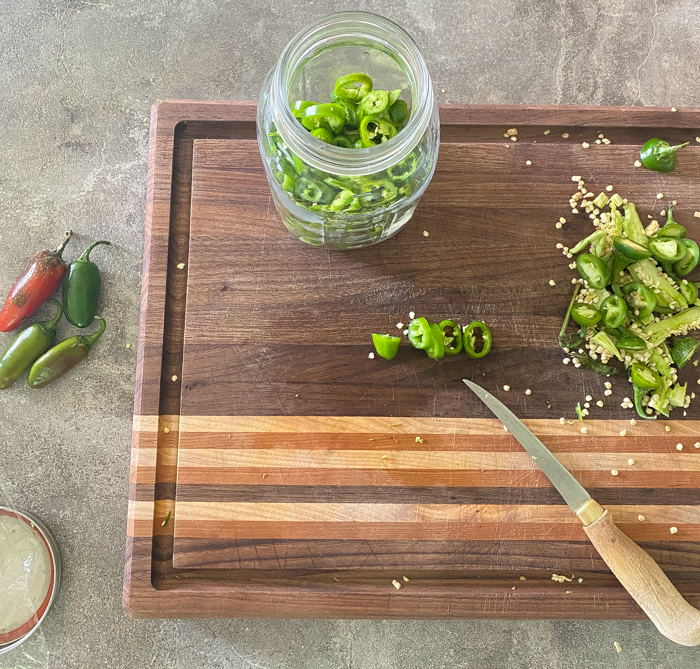 Cutting board filled with sliced jalapeños for fermenting.