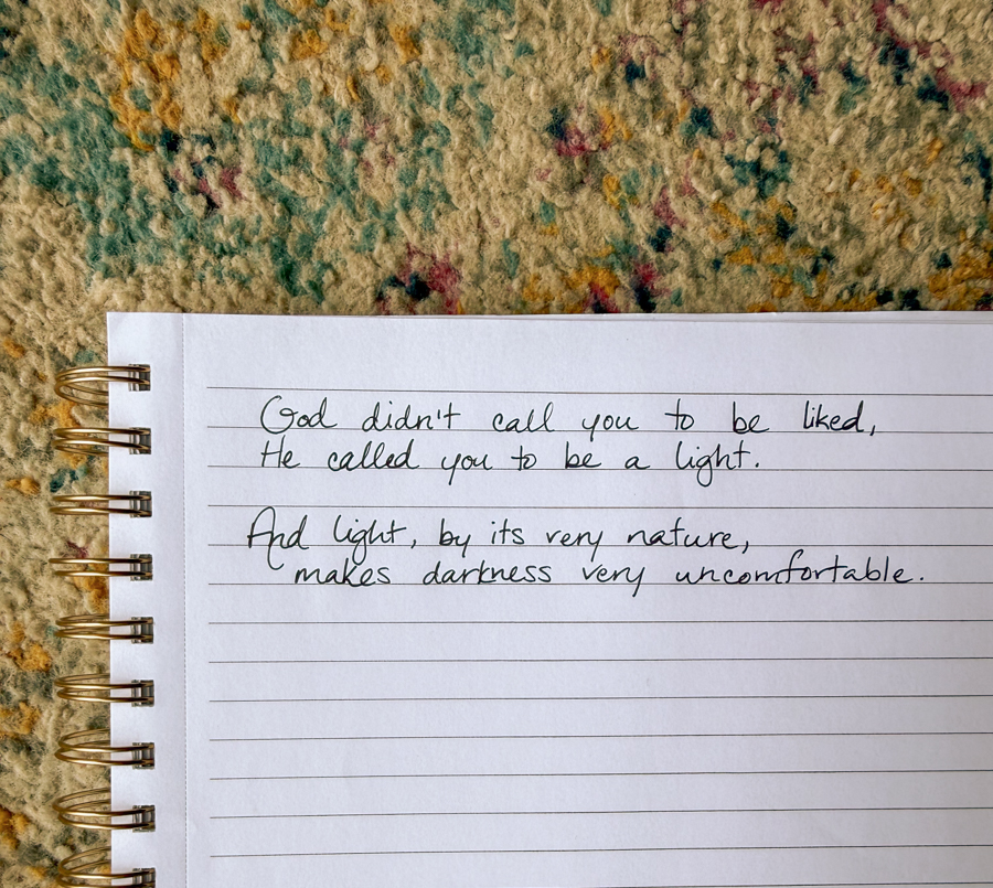 A notebook with the writing, "God didn't call you to be liked, He called you to be a light. And light, by its very nature, makes darkness very uncomfortable."