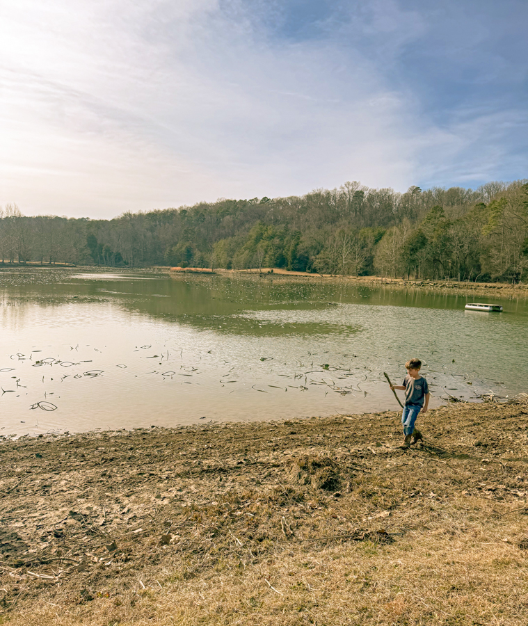 A little boy walking along a riverbank.