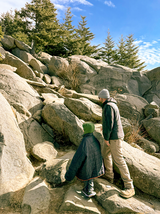 A little boy and his father climbing rocks.